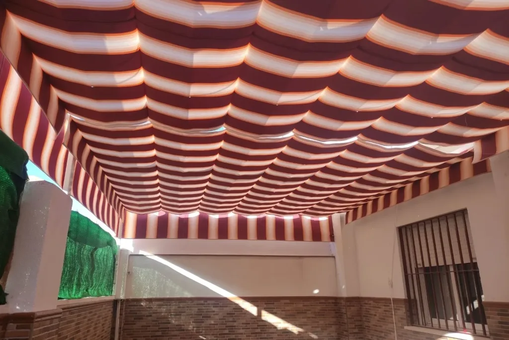 Toldo plano de palillería con lona a rayas rojas y blancas, visto desde abajo