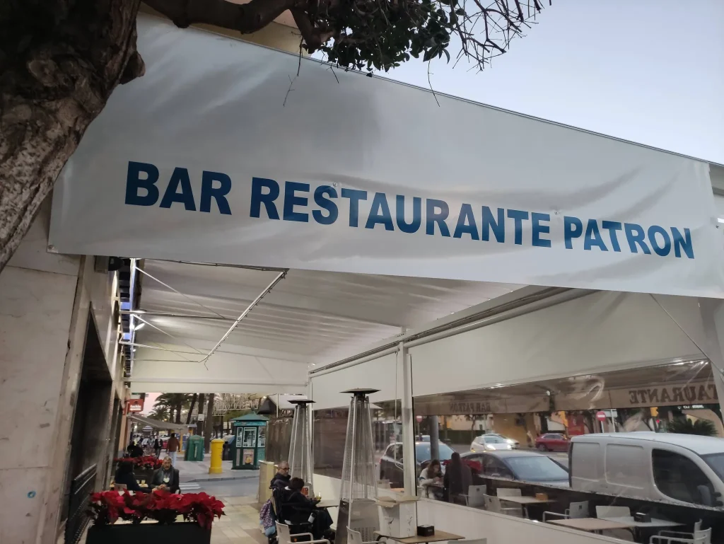 Terraza del Bar Restaurante Patrón cubierta con toldo de lona y cerrada con cortavientos